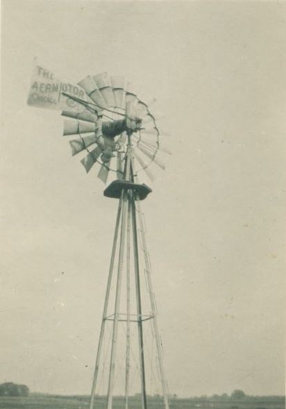 Black and white photo of young Esco doing an upside-down L-sit on top of a windmill on his family farm