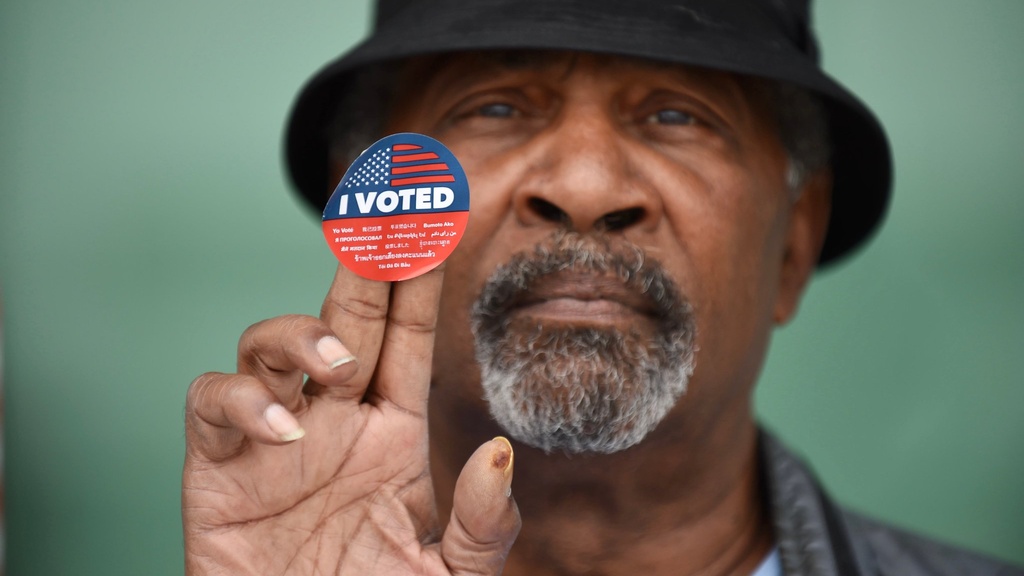 African American man holding "I voted" sticker
