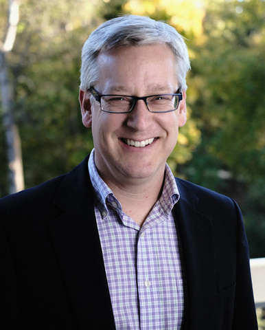 a man with grey hair, glasses, and a purple button-up shirt