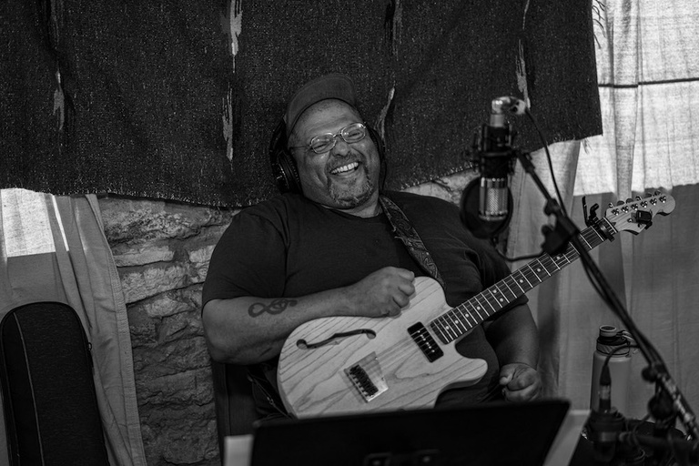 A man laughs while holding a guitar.