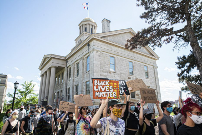 People holding Black Lives Matter signs with an old building with columns and a cupola in the background.