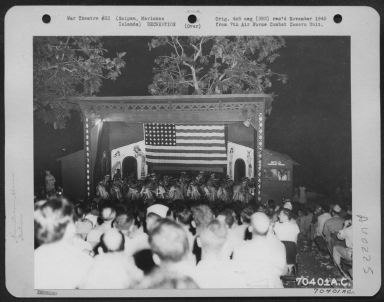 People dressed in traditional Pacific Islander costume dance on a stage for US service members
