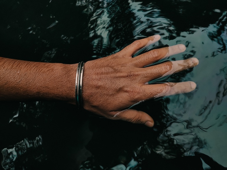 Hand with bracelet touching water