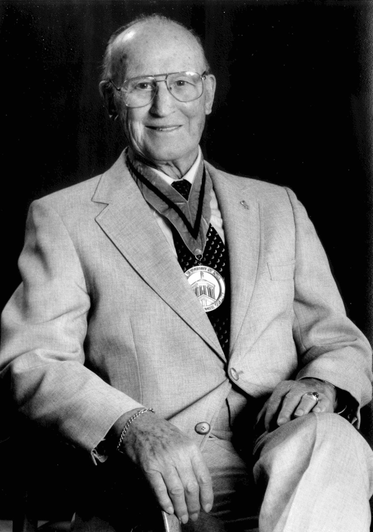 A Black & White photo of Esco Obermann sitting down and smiling and wearing a medal.