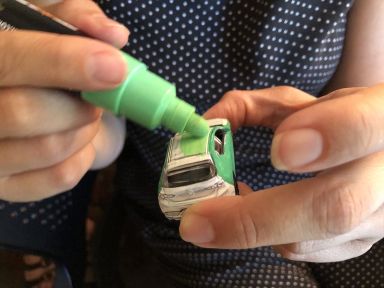 hands painting a toy car