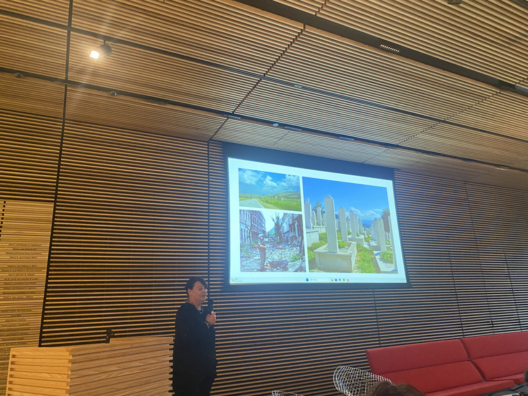 faculty member speaking while showing photos on a screen at art museum