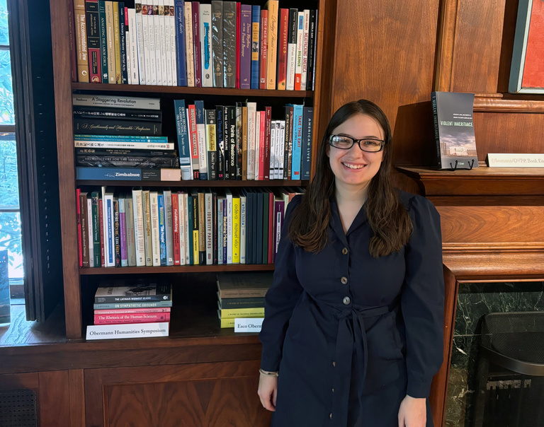 Eleanor Ball standing by Obermann library shelves