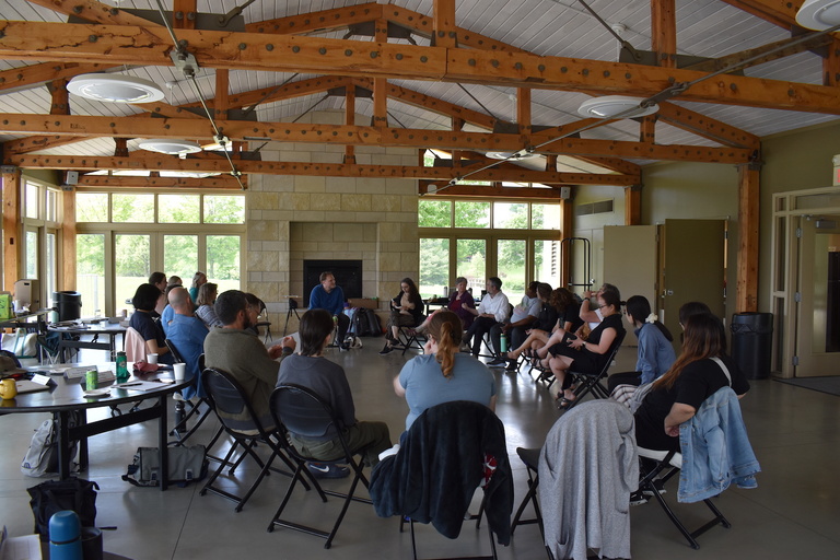 Writers sit in circle, listening to speaker